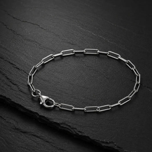 Feines Paperclip Herren Armband mit Karabinerverschluss aus silberfarbenem Edelstahl auf dunkler Schieferplatte.