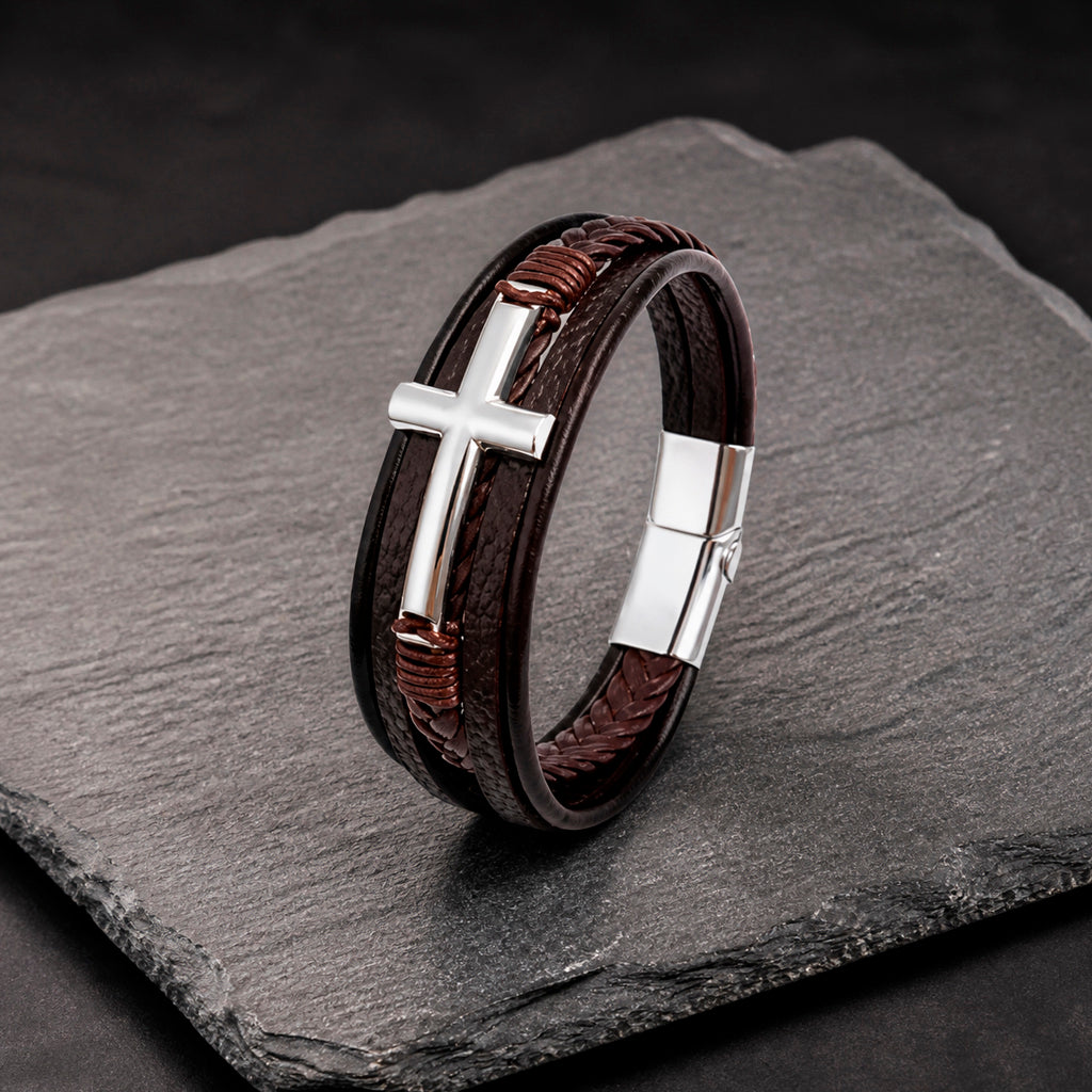 Lederarmband in braun für Männer mit 5 Strängen geflochten und glatt und mit Kreuz aus silbernem Edelstahl auf einer Schieferplatte