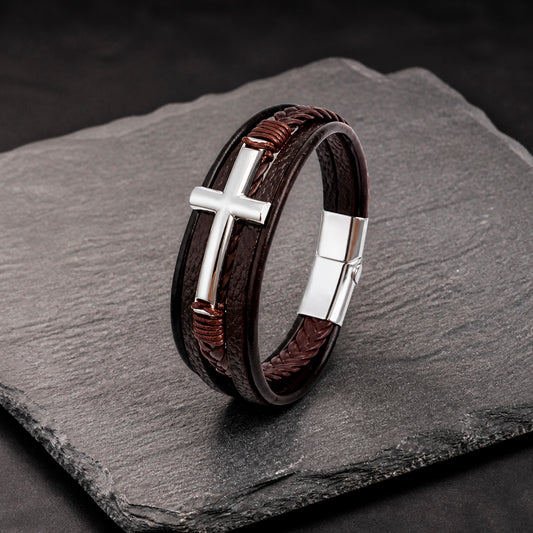 Lederarmband in braun für Männer mit 5 Strängen geflochten und glatt und mit Kreuz aus silbernem Edelstahl auf einer Schieferplatte