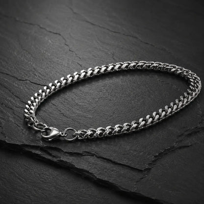 Silberfarbenes Herren Armband aus Edelstahl mit Karabinerverschluss auf dunkler Schieferplatte.