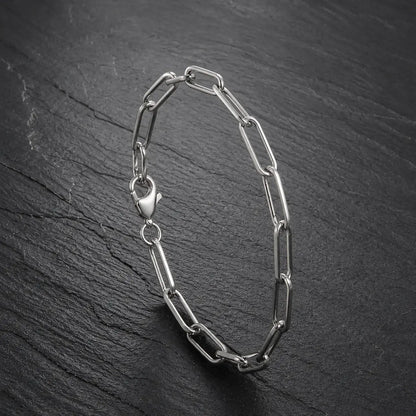 Silberfarbenes Paperclip Herren Armband aus Edelstahl auf dunkler Schieferplatte.