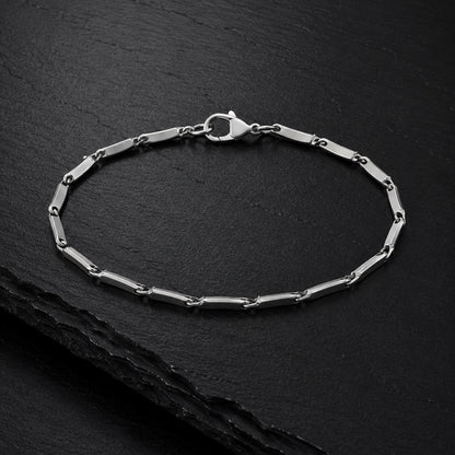 Facettiertes Herren Armband aus Edelstahl auf dunkler Schieferplatte.
