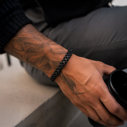 Schwarzes Herren Lederarmband mit Edelstahlelementen am tätowierten Handgelenk getragen.