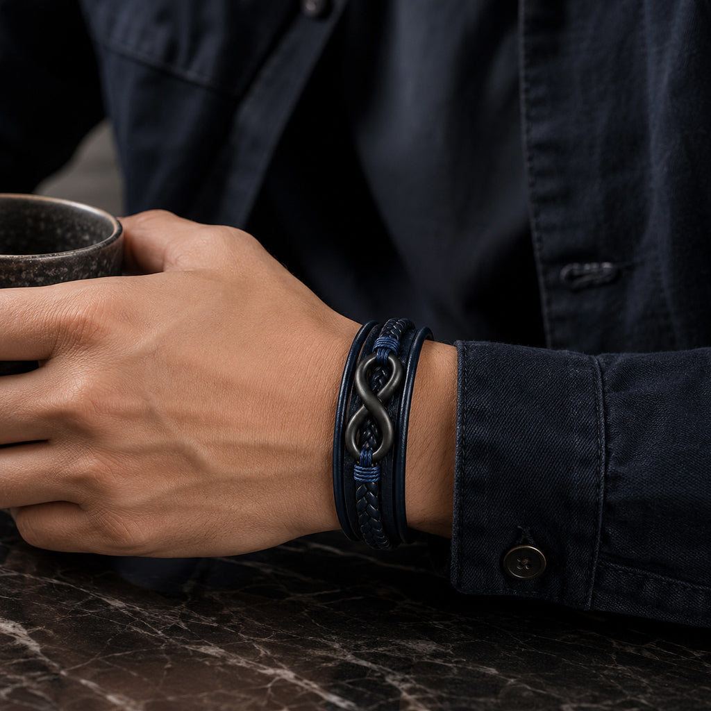 Lederarmband in blau für Männer mit 5 Strängen geflochten und glatt und mit Infinite Zeichen aus schwarzem Edelstahl wird von einem Mann getragen