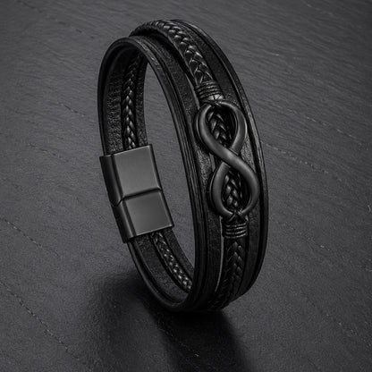 Lederarmband in schwarz für Männer mit 5 Strängen geflochten und glatt und mit Infinite Zeichen aus schwarzem Edelstahl auf einer Schieferplatte
