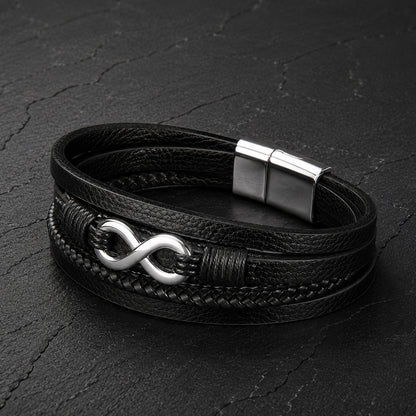 Mehrsträngiges schwarzes Herren Lederarmband mit Infinity Symbol auf Schieferplatte.