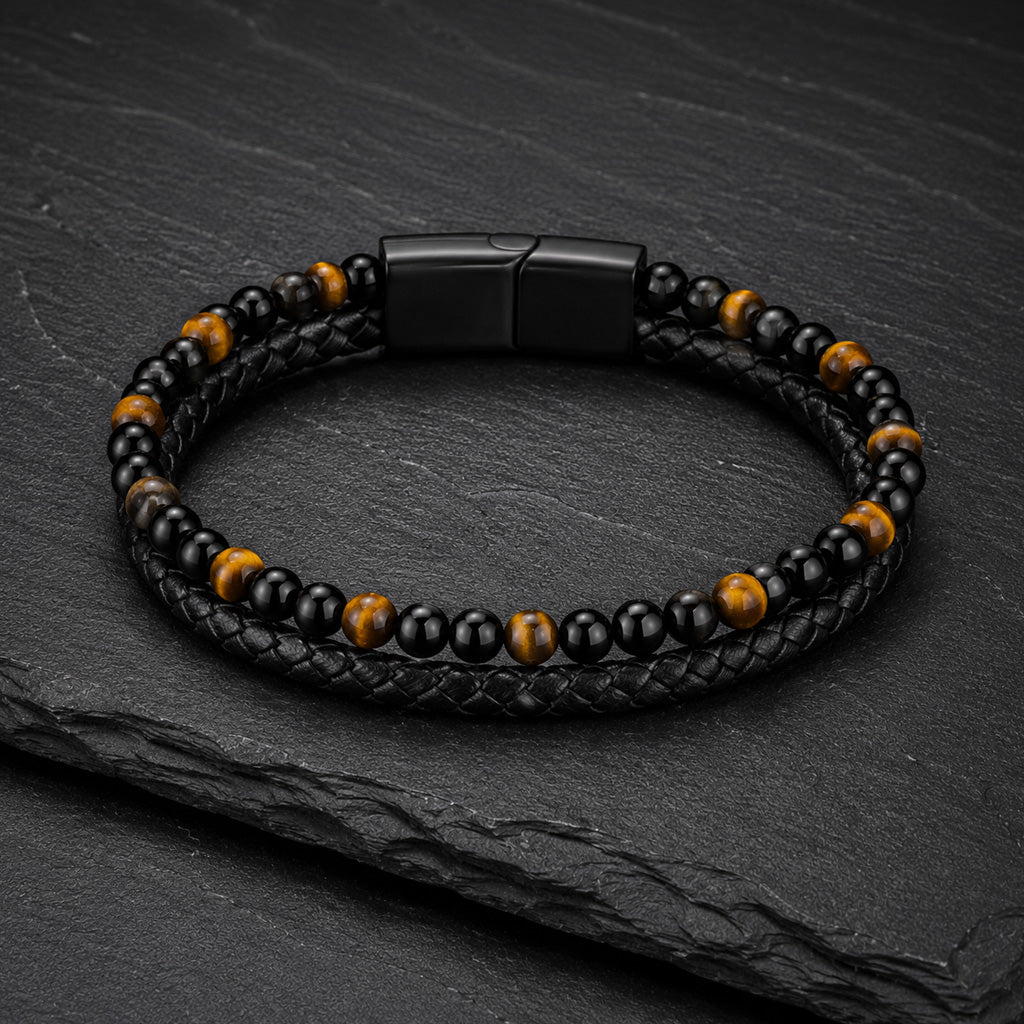 Schwarzes Herren Lederarmband mit Tigerauge Perlen auf dunkler Schieferplatte.