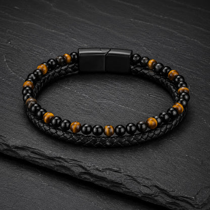 Schwarzes Herren Lederarmband mit Tigerauge Perlen auf dunkler Schieferplatte.