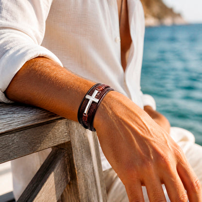 Lederarmband in braun für Männer mit 5 Strängen geflochten und glatt und mit Kreuz aus silbernem Edelstahl wird von einem Mann getragen